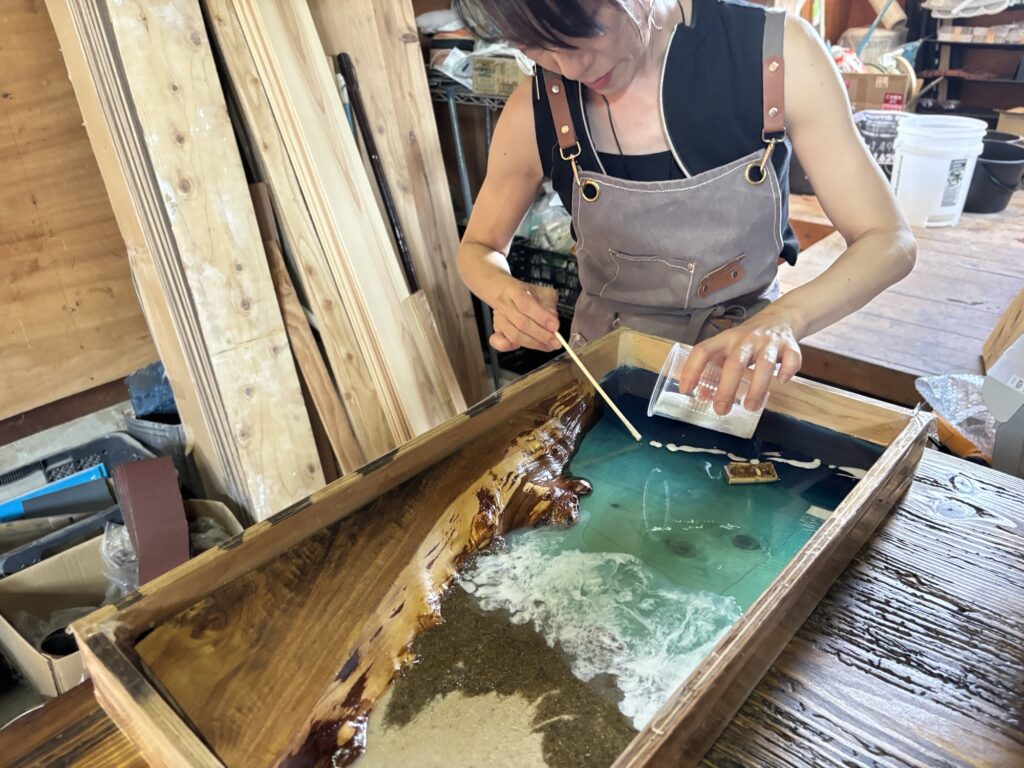 エポキシレジンで波の泡を描く女性参加者の制作風景