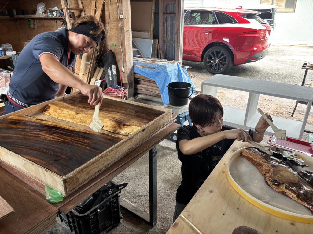 レジンテーブル制作体験で木材の表面にオイルを塗る参加者の様子