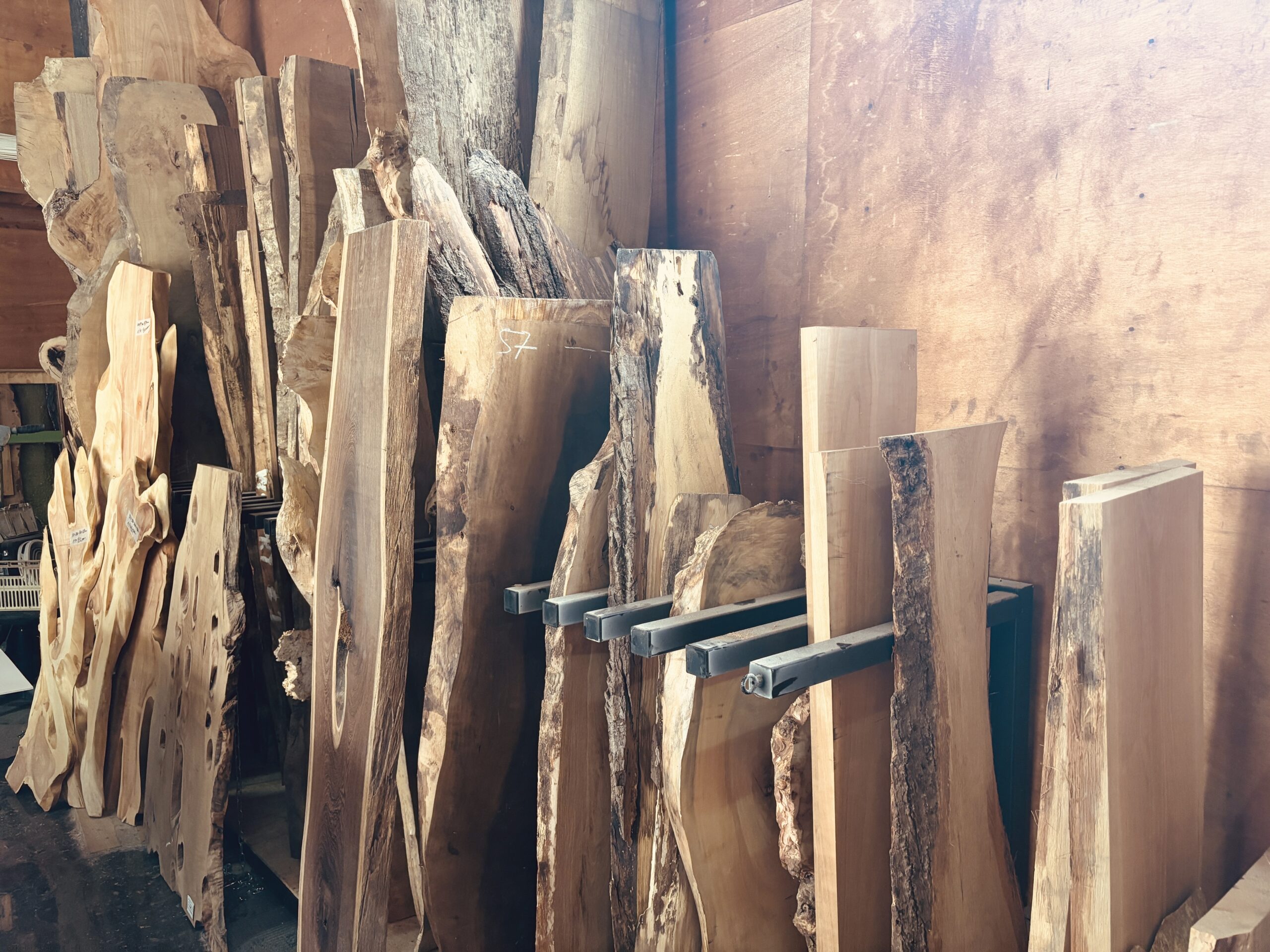 多彩な樹種の一枚板が整然と並ぶ工房内のストック材
