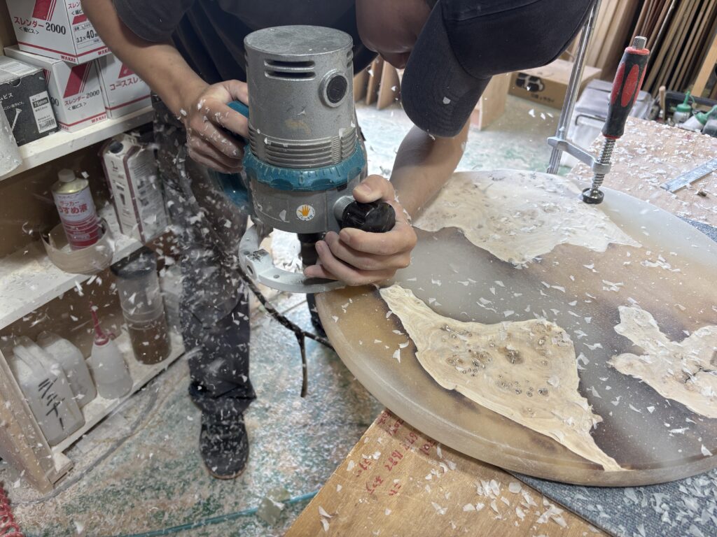 レジンテーブルの縁をトリマーで加工する新人スタッフさん