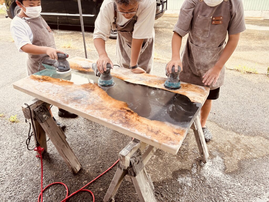 家族4人で電動サンダーを使い研磨するレジンテーブル制作体験