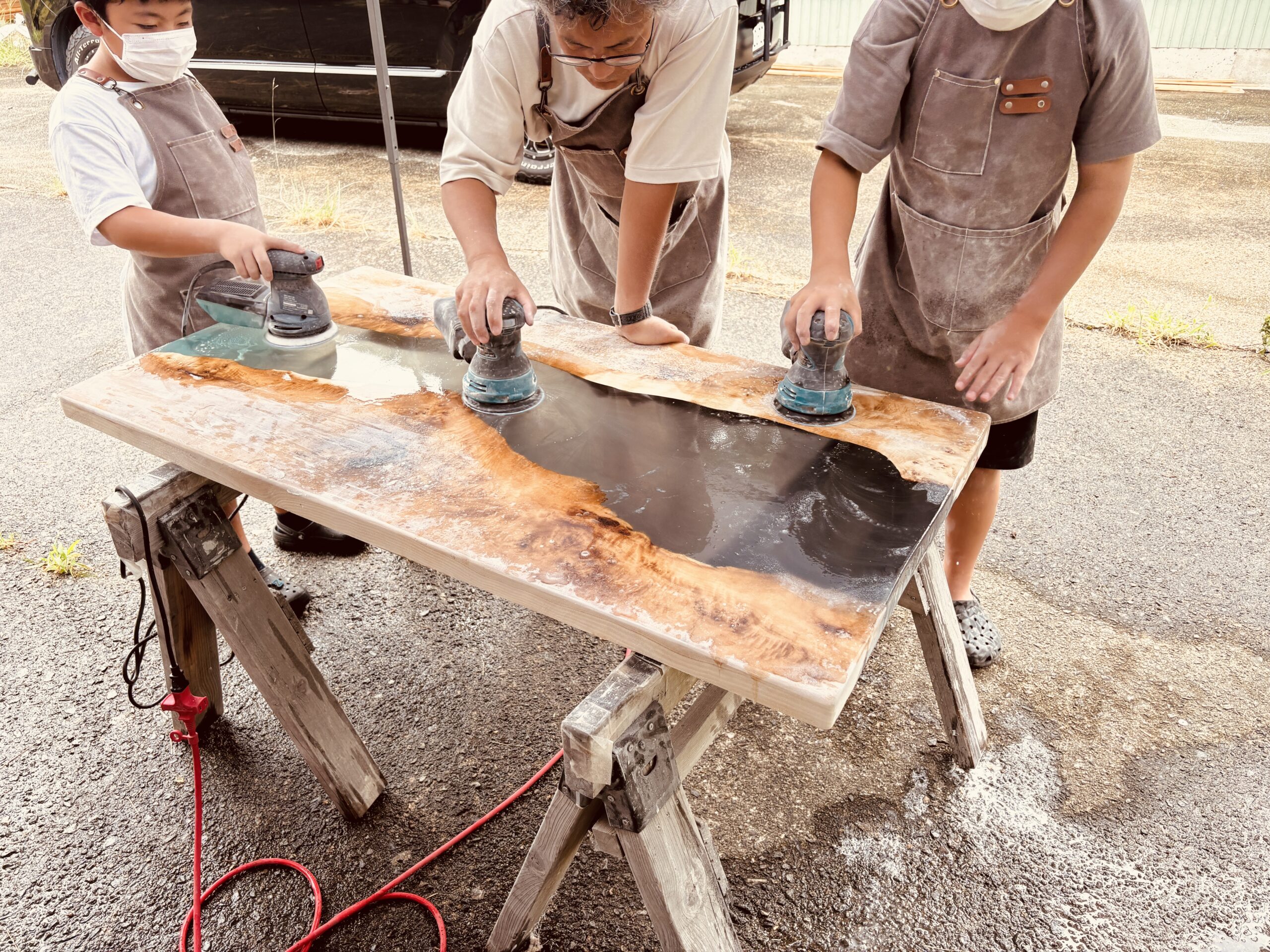 家族4人で電動サンダーを使い研磨するレジンテーブル制作体験