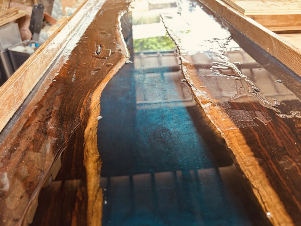 レジンテーブル制作体験ワークショップで受講生がアフリカンブラックウッドにブルーレジンを流し込む様子