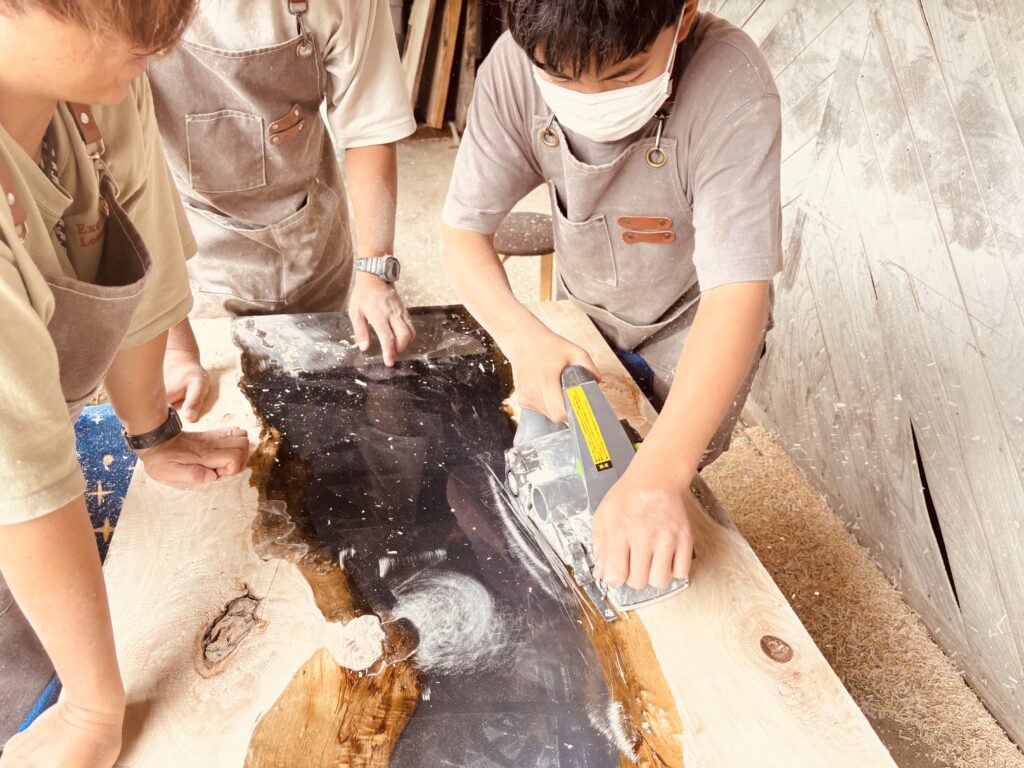 中学生が電動かんなを操作し木部を整える様子