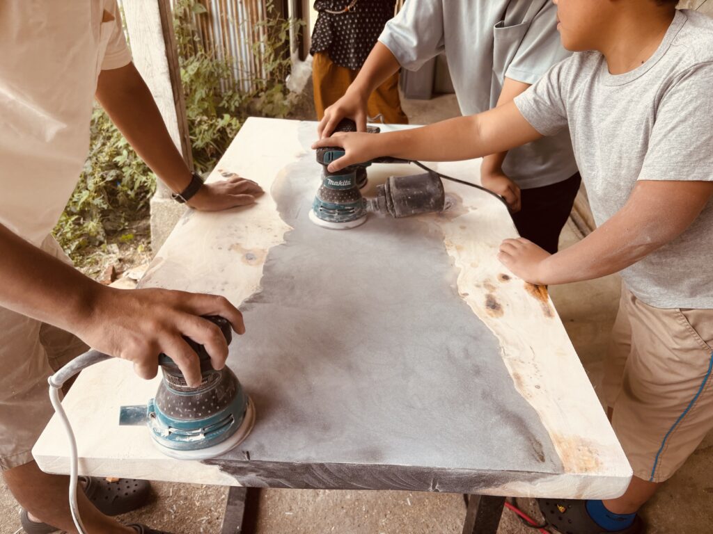 家族でレジンテーブルの表面をサンダーで研磨している様子