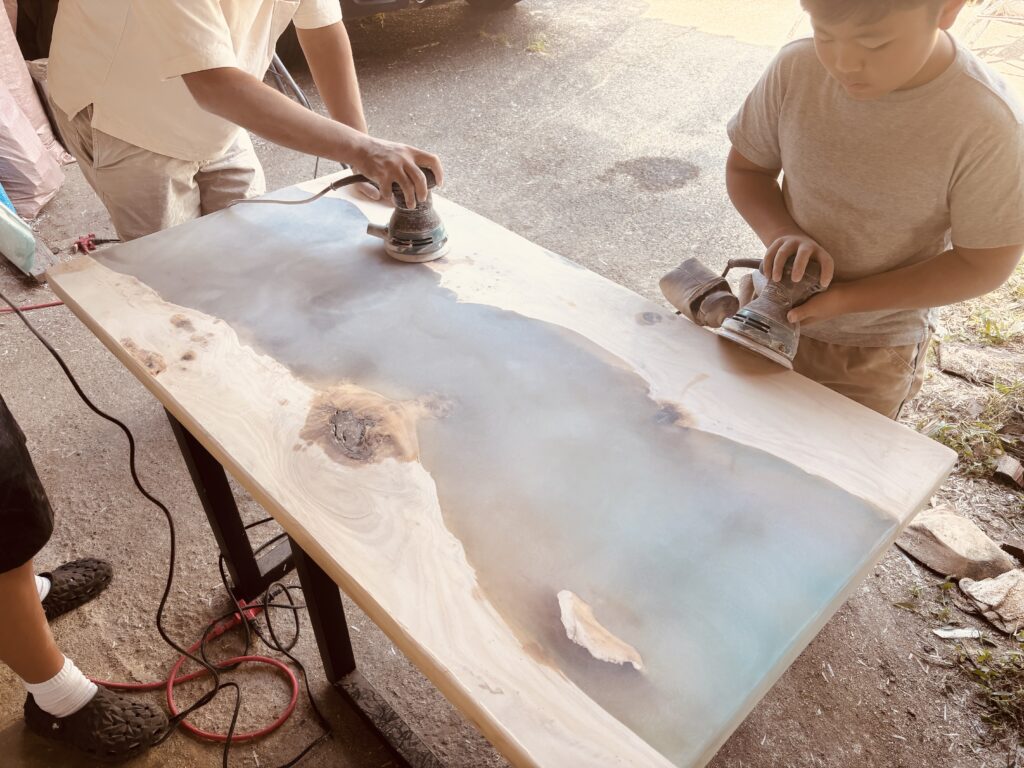 子供が真剣な表情でレジンテーブルの表面を研磨している様子