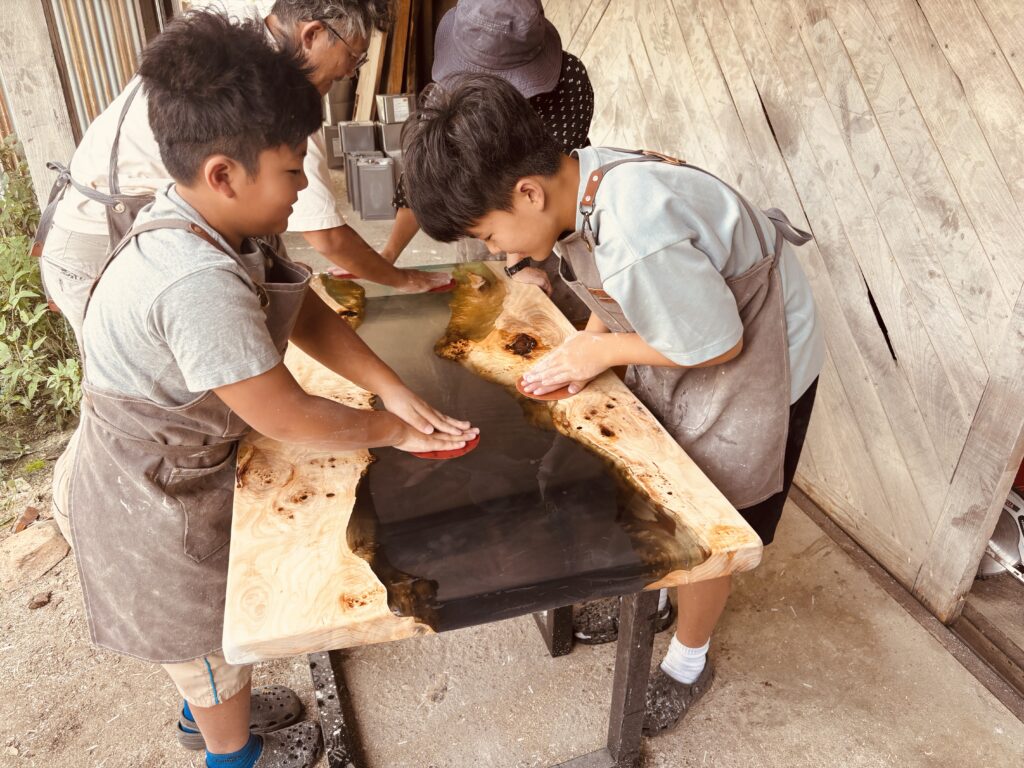 家族でレジンテーブルを水研ぎして表面を磨き上げている様子