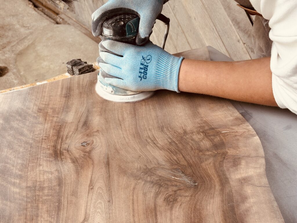 新入社員と一緒にレジンテーブルをサンダーで研磨する様子