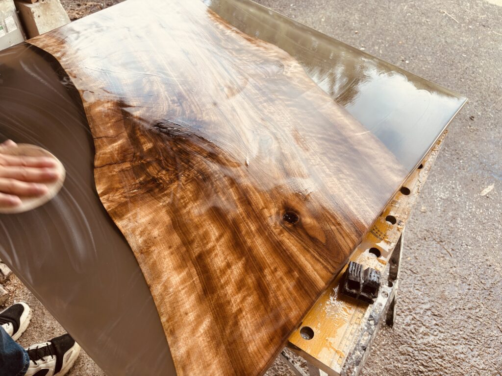 ブラックウォルナットの木目が浮かび上がるレジンテーブルの仕上げ磨き