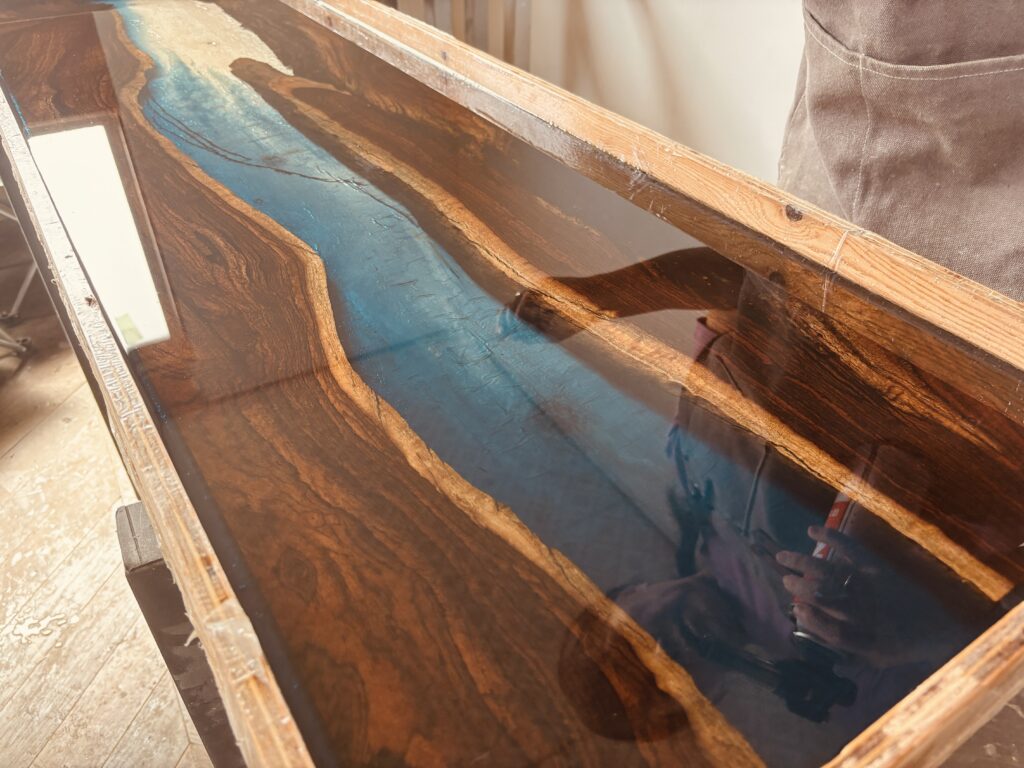 硬化中のレジンテーブルに映り込む作り手の姿とブルーの透明感