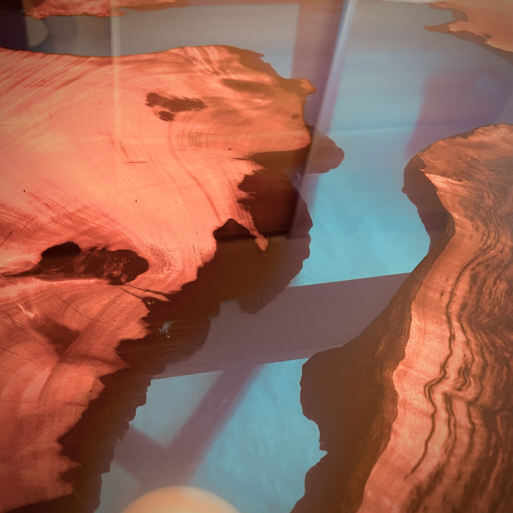 カンファーウッドの力強い木目とブルーレジンの透明感が交差する部分をアップで撮影した写真。木の質感が際立っている。