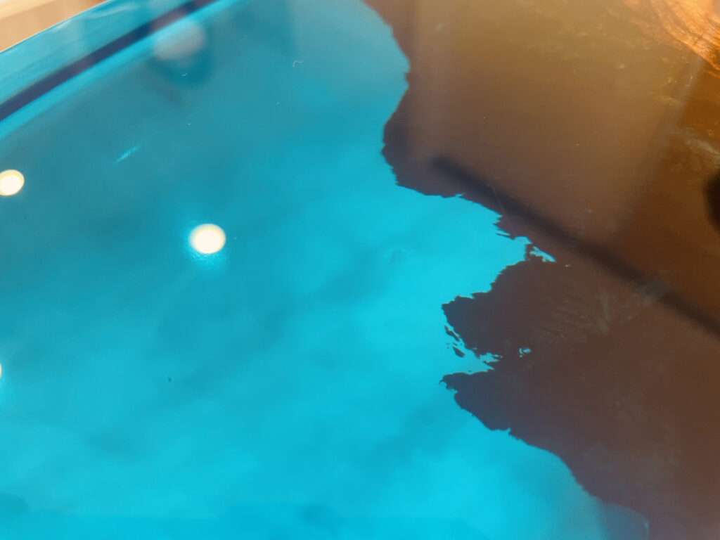 透明感のあるブルーのレジン表面をクローズアップした写真。カンファーウッドの端部と青いレジンの境界が美しく映っている。