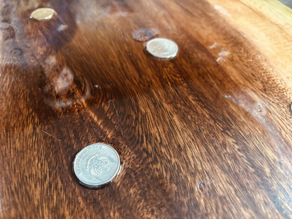 レジンの中に埋め込まれた古銭とモンキーポッドの木肌をアップで撮影した写真。