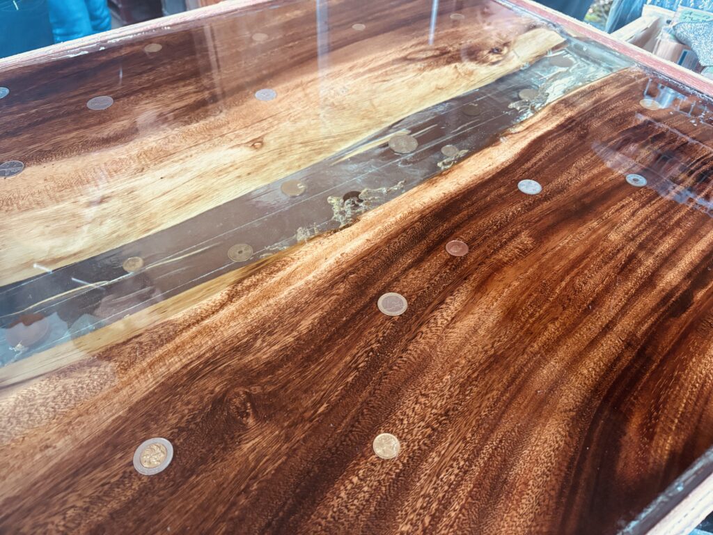 モンキーポッドと淡いグリーンのレジンを組み合わせ、古銭や海外コインを散りばめたレジンテーブルを製作中の様子。