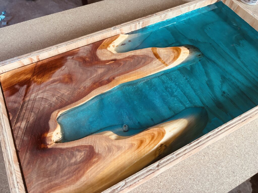 ブルーグリーンのレジンが広がる入江形状と、カイヅカイブキの温かみある木肌が調和したレジンテーブル天板の全景。