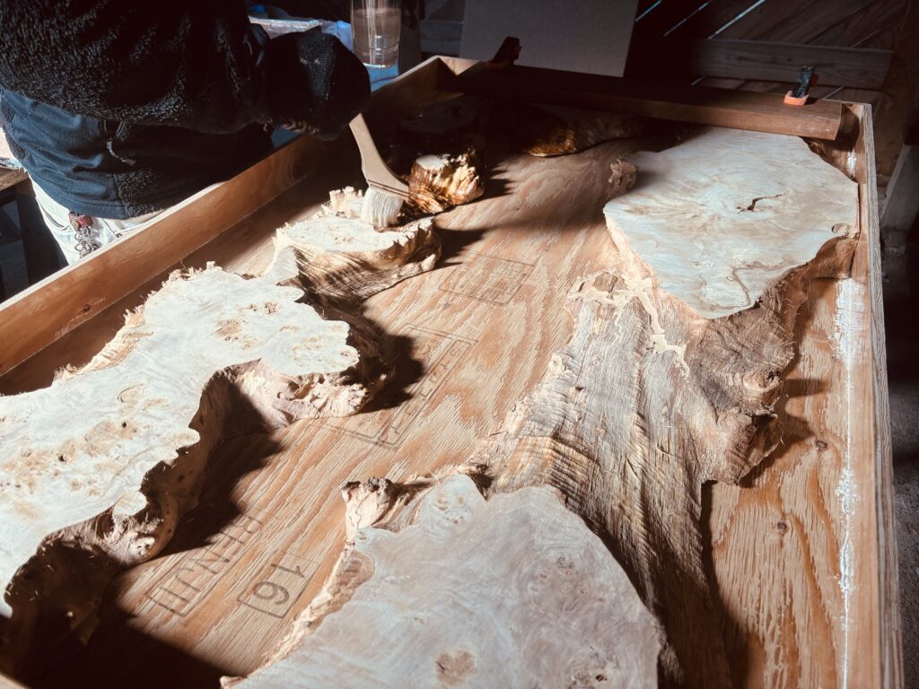 参加者が刷毛でポプラ材の表面にシーリングを行っている様子。凹凸の深さや木目の複雑さが強調されている。