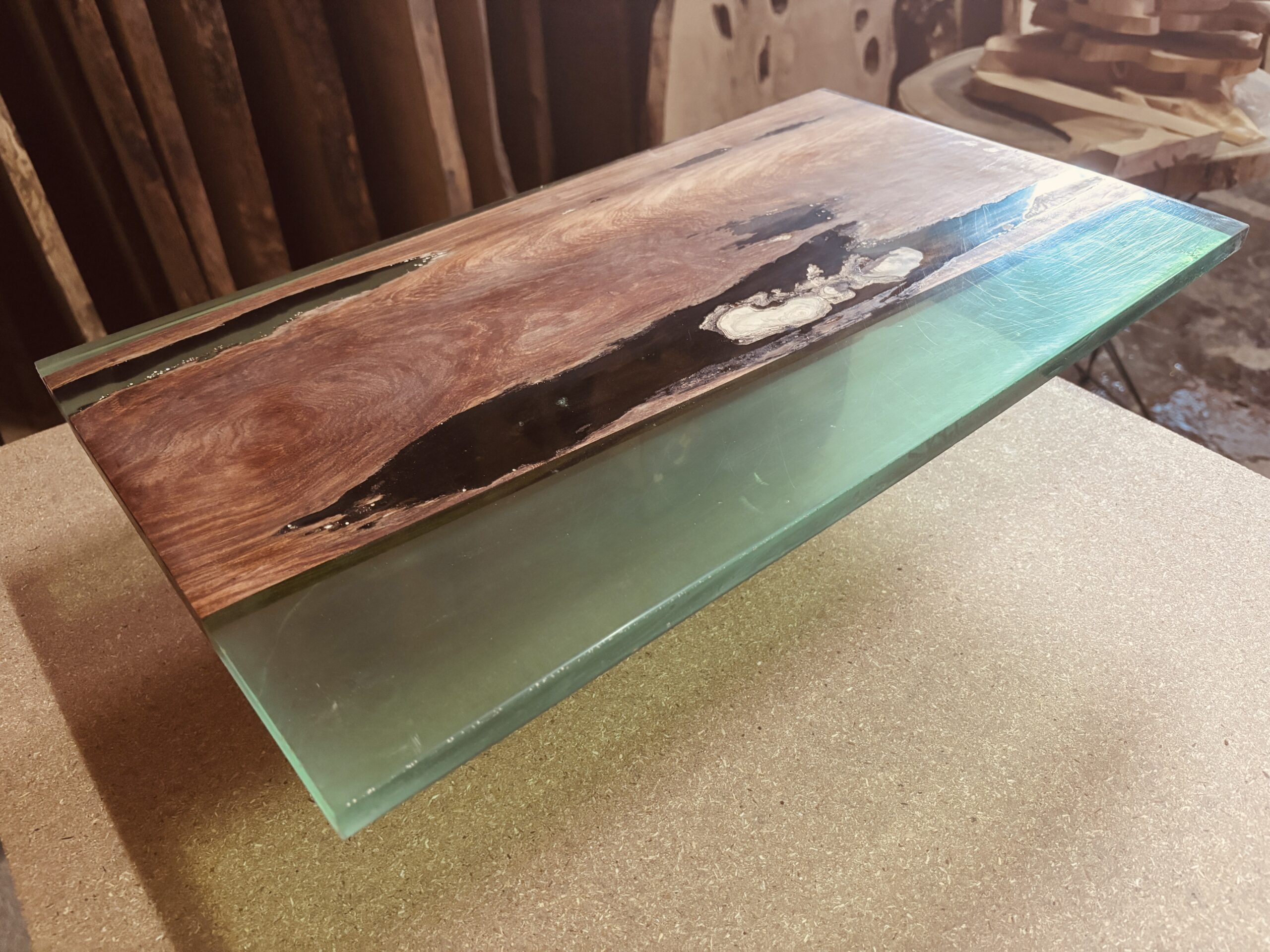 パオロサ材と透明感のあるグリーンレジンを組み合わせたレジンテーブル天板。深い色味の木目とクリアなレジンが対比的に輝く仕上げ。