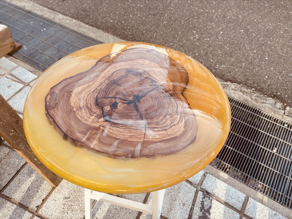 オリーブ材とラメ入りオレンジレジンを組み合わせた丸型レジンテーブル。木目とレジンが溶け合う鮮やかな仕上がり。