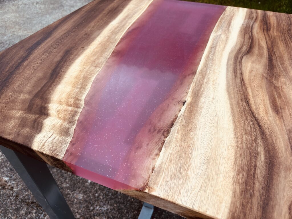 ピンク色のレジンを流し込んだレジンテーブル。無垢材の表情と華やかな色合いが特徴