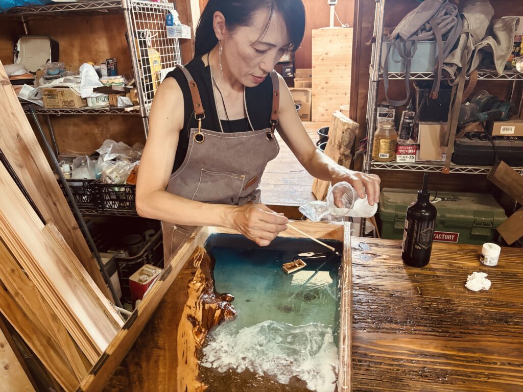 レジンテーブル製作体験で、参加者が型枠の中に色付きレジンを丁寧に流し込んでいる工程写真