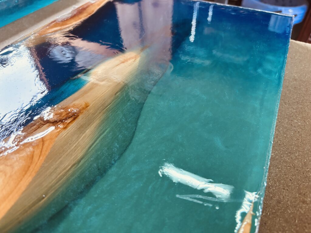 濃いブルーとスカイブルーのレジンが流し込まれたサイドテーブル用レジン天板。硬化後の表情が確認できる。