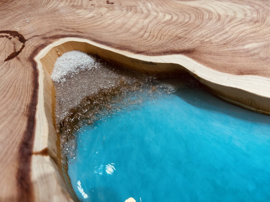 カイヅカイブキの輪切り材を入江に見立て、本物の砂で砂浜を表現した海イメージのレジンテーブル制作途中