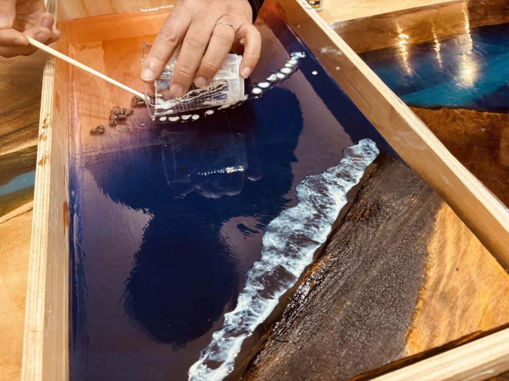 初めてのレジンテーブル制作体験で、スティックを使って自然な波の表情を描いている手元のアップ写真