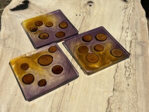 紫と黄色のグラデーションレジンの中にウッドスライスを閉じ込めたコースターの完成見本。