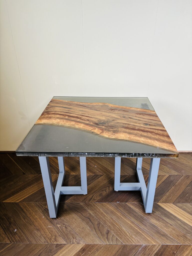 ブラックウォルナットを斜めに配置し、スモーキーグレーのレジンを両サイドに流し込んだ850mm角のレジンテーブル。グレーのアイアン脚とヘリンボーン床が調和した正面アングル。