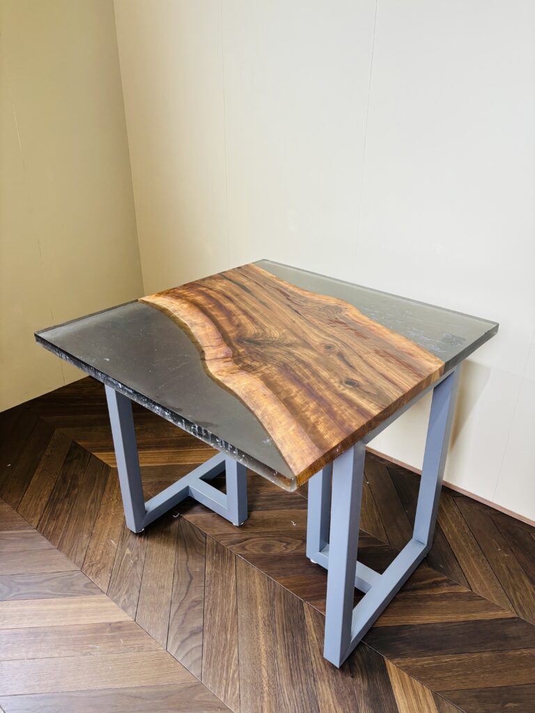 ブラックウォルナットを対角に配置し、スモーキーグレーのレジンが周囲を包む850mm角のレジンテーブルを斜め上から撮影した写真。