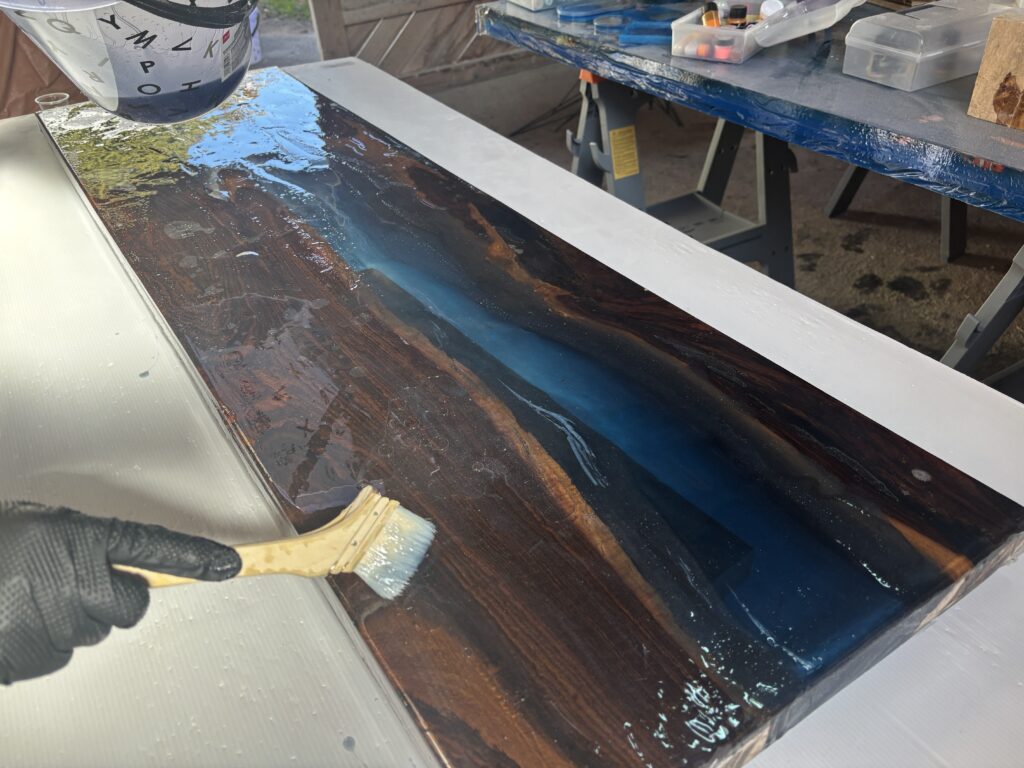 レジンテーブル制作体験で刷毛を使い、裏面からブルーパールのレジンを塗り広げている作業風景