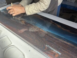 速乾性レジンを使い、裏側から細かな線や流れを描き込んでいるレジンテーブル制作体験の様子