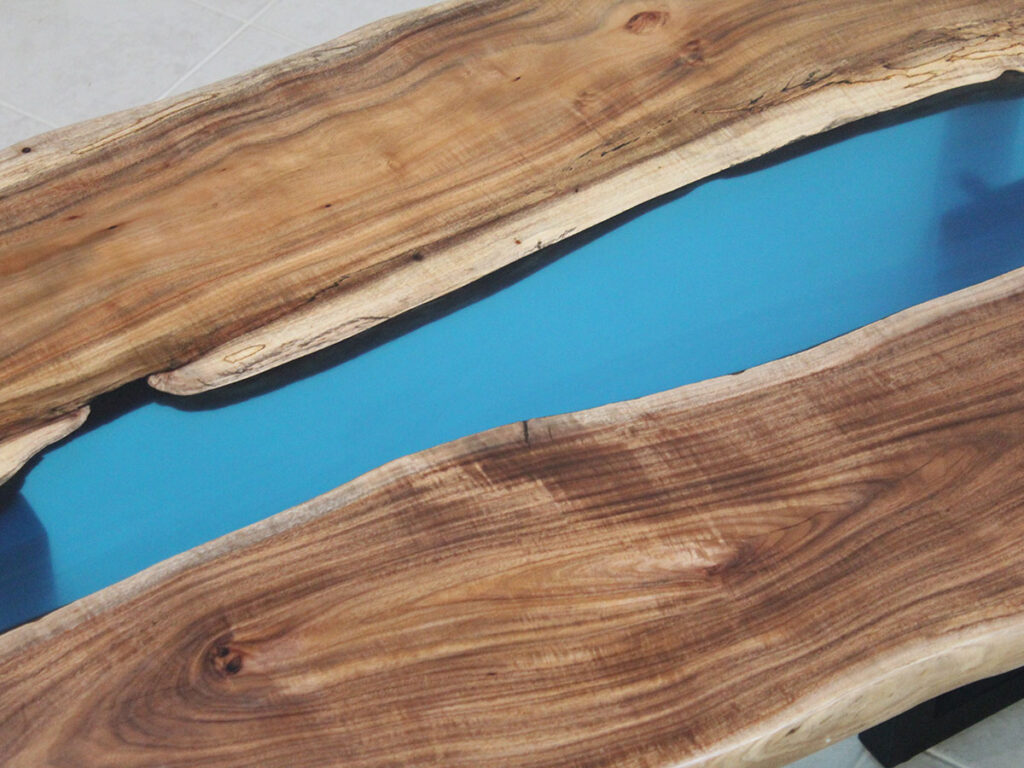 一枚板の天然木にブルーのレジンを流し込んだレジンテーブル。木目とレジンの境界が自然に揺らぐデザイン。