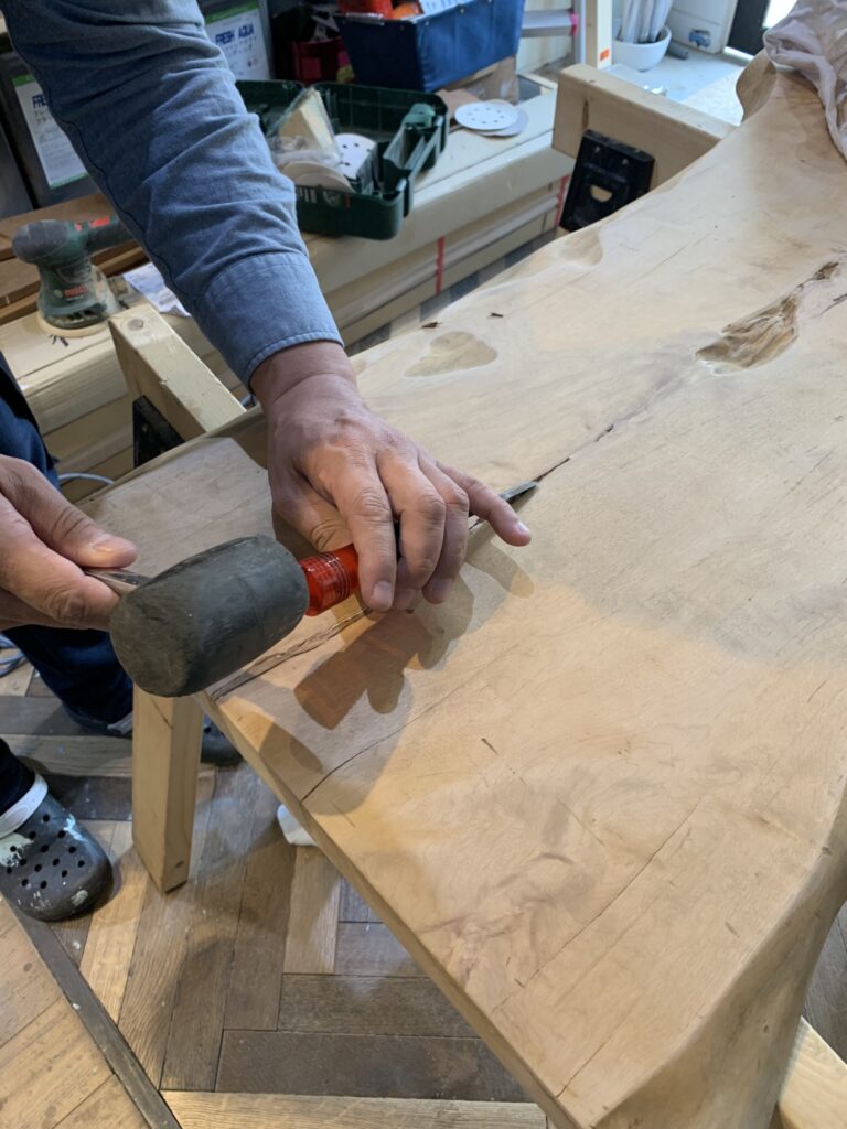 トチノキの割れ部分をノミで整え、レジンを流し込む前の下地処理を行っている様子。