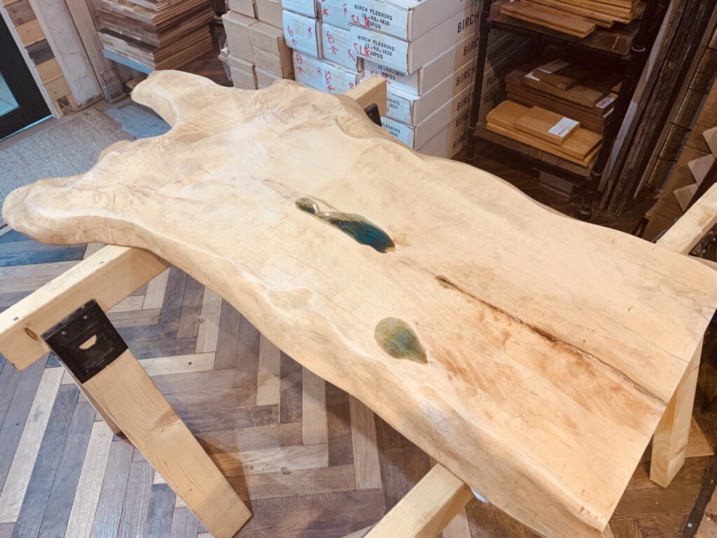 作業台の上で仕上げ前のトチノキのレジンテーブル全体を確認している様子。