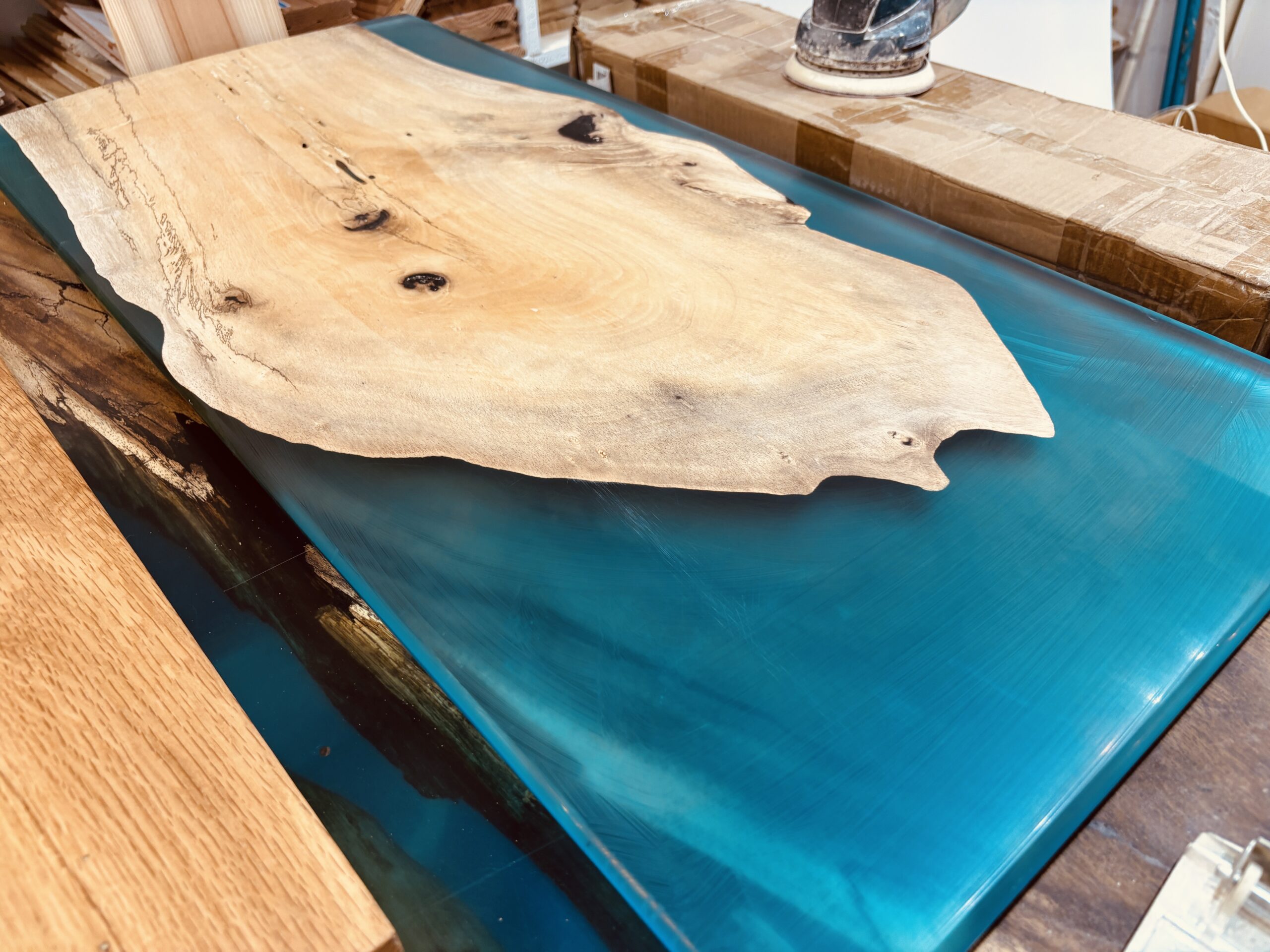 カキノキ無垢材とブルーのレジンを組み合わせたリバータイプのレジンサイドテーブル上面