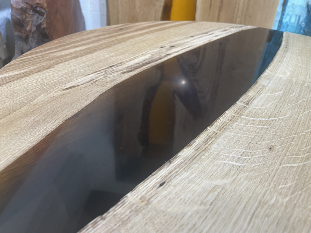 オーク材の木目とブラックレジンの境界部分をクローズアップしたラウンドレジンテーブル