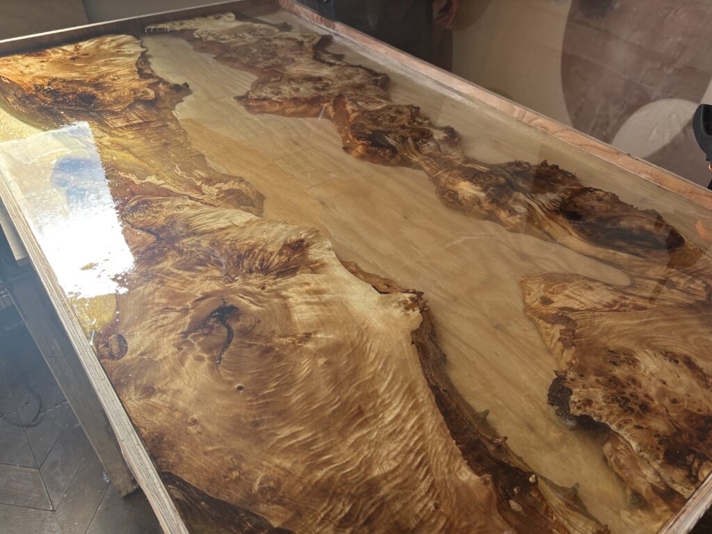 ポプラの一枚板とゴールドレジンを組み合わせたレジンテーブルを、フルカバー仕上げで流し込み直後の状態。木目の際まで透明感のあるレジンが広がっている様子。