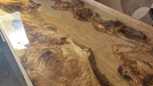 ポプラの一枚板とゴールドレジンを組み合わせたレジンテーブルを、フルカバー仕上げで流し込み直後の状態。木目の際まで透明感のあるレジンが広がっている様子。