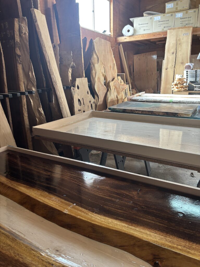 御所市のアトリエ内で、木枠に入ったレジンテーブル用の型や一枚板が並び、制作が同時進行している作業風景。