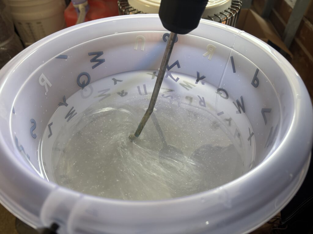 低温のアトリエで、電動ミキサーを使って透明レジンを慎重に撹拌している様子。