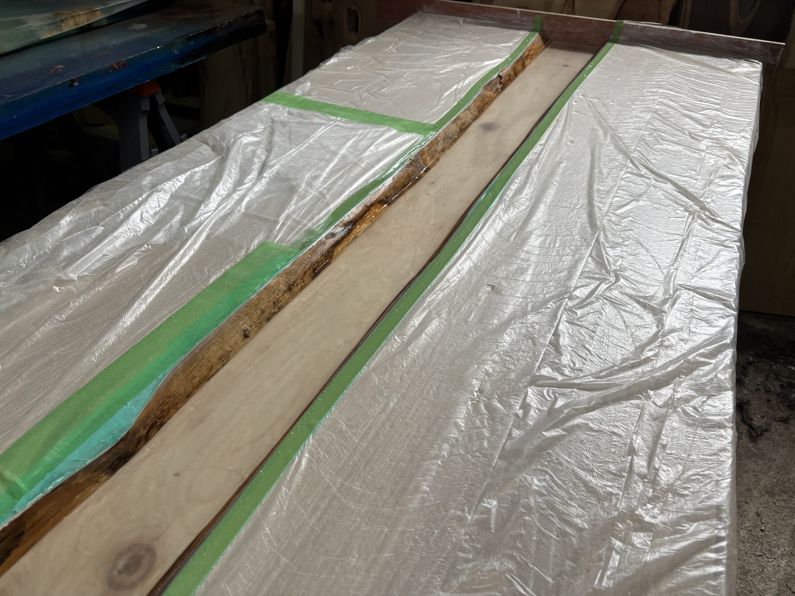 両耳付きのチェスナット材を使い、木枠を使わずに養生とマスキングでレジン流し込みの準備をしている制作途中のレジンテーブル。