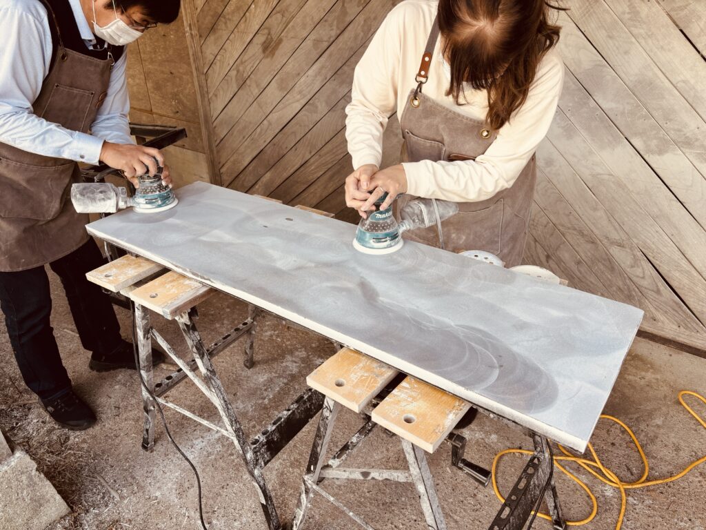 御所市のレジンテーブル製作体験でご夫婦が並んでオービタルサンダーで天板を研磨している様子