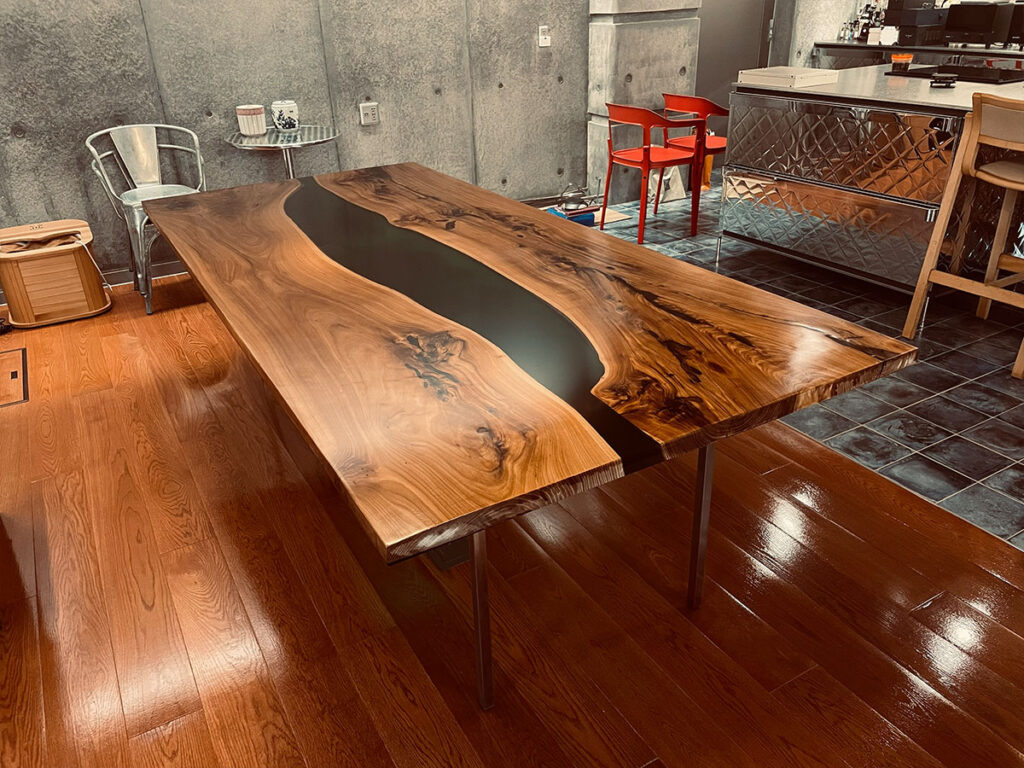 カンファーウッド（クスノキ）の無垢一枚板を使用した幅1100mm・長さ2400mm・厚さ60mmの大型レジンテーブル。ブラックレジンが流れるように配置されたダイニングテーブル。