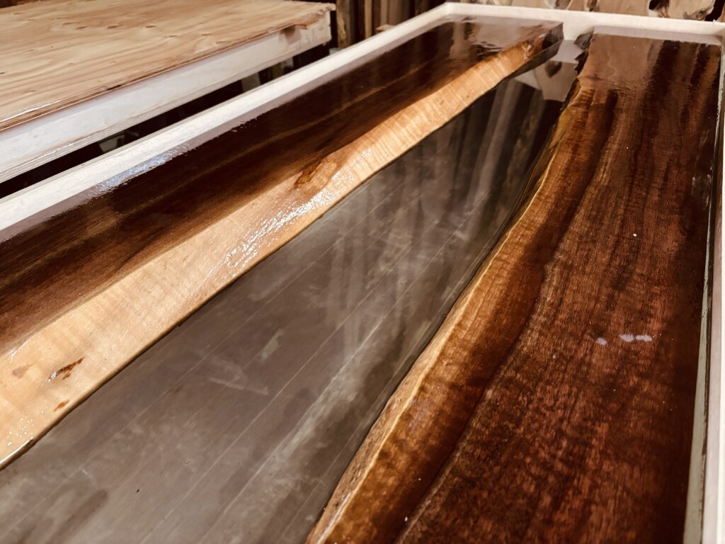 ブラックウォルナットの耳付き一枚板の間にスモークグレーのレジンが流れる制作途中のレジンテーブル。